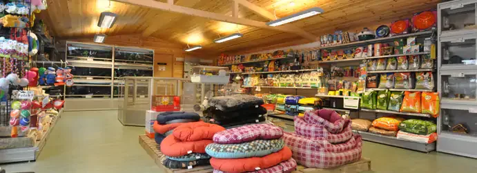Raflarında köpek maması, oyuncak ve köpek yatakları bulunan geniş bir pet shop iç mekânı.